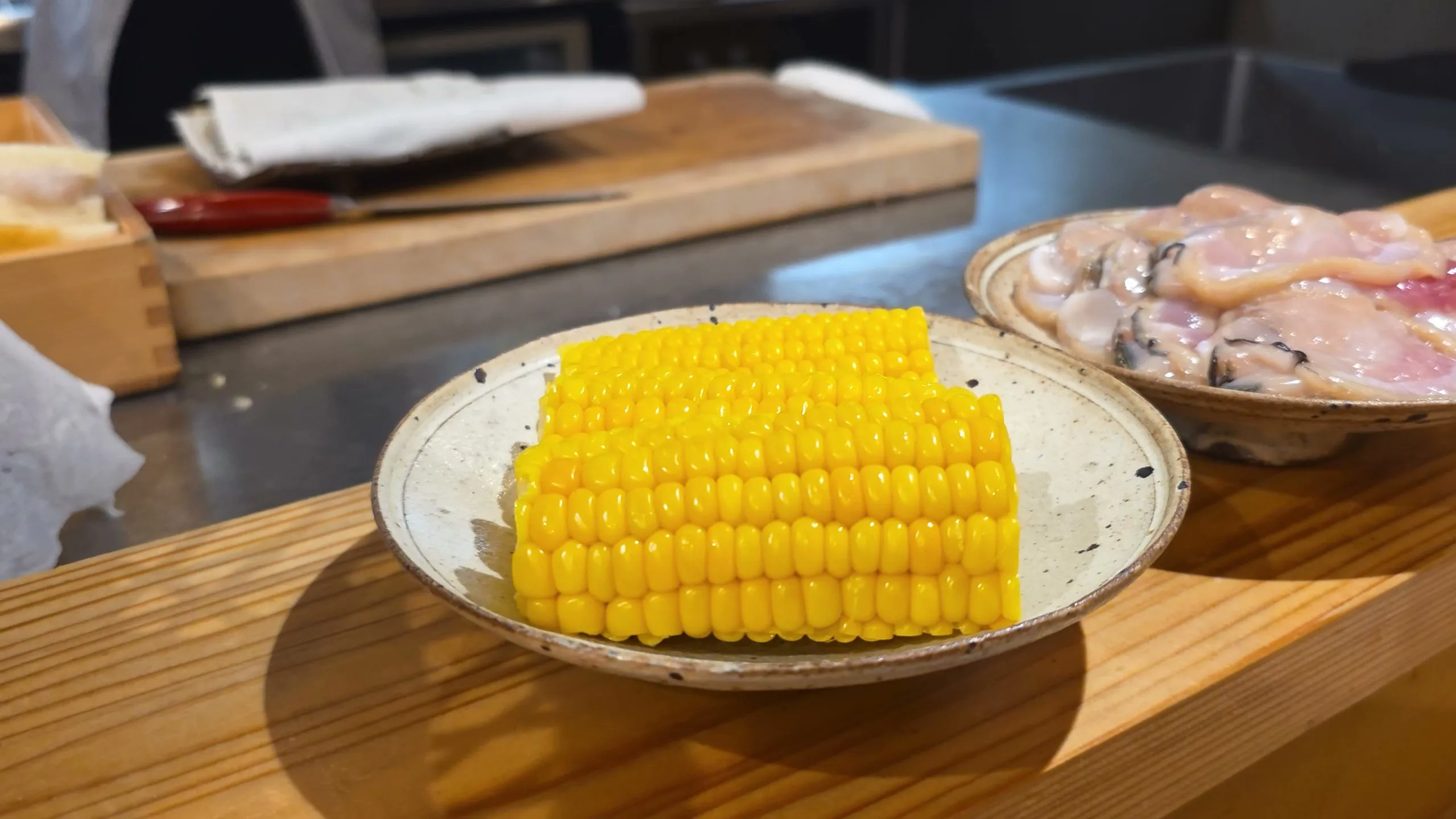Corn and shelled clams in ceramic dishes on the Asanuma counter before frying