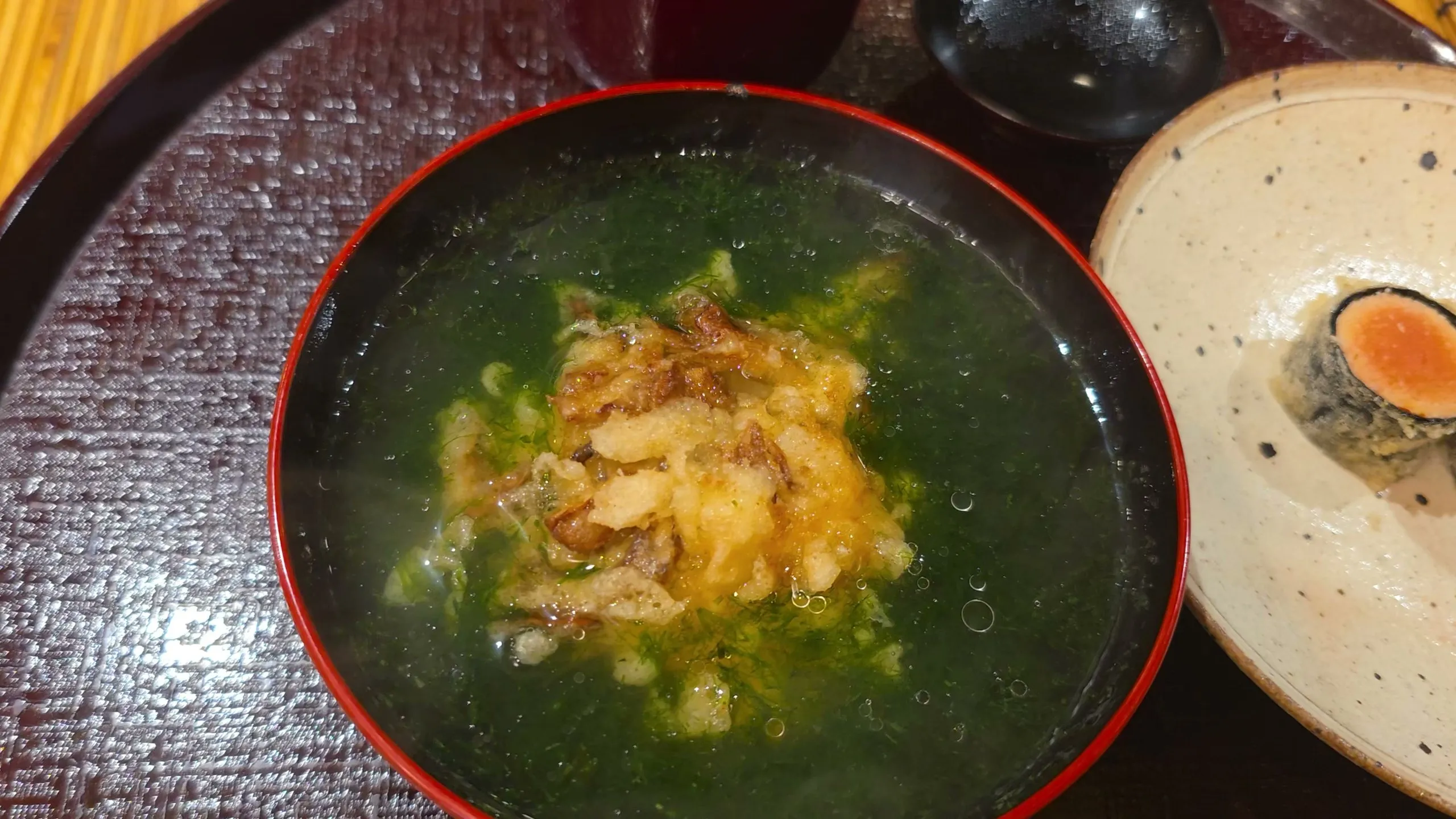 Tencha, a kakiage fritter in broth thick with green aonori, beside fried mentaiko